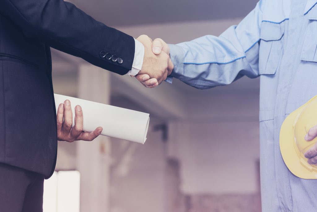 architect engineer shaking hands with businessman on site